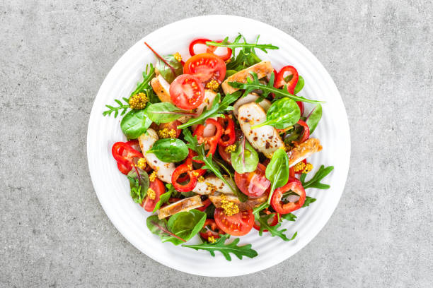 Fresh vegetable salad plate of tomatoes, spinach, pepper, arugula, chard leaves and grilled chicken breast. Fried chicken meat, fillet with salad. Healthy food. Diet dinner or lunch. Salad plate on table. top view stock photo