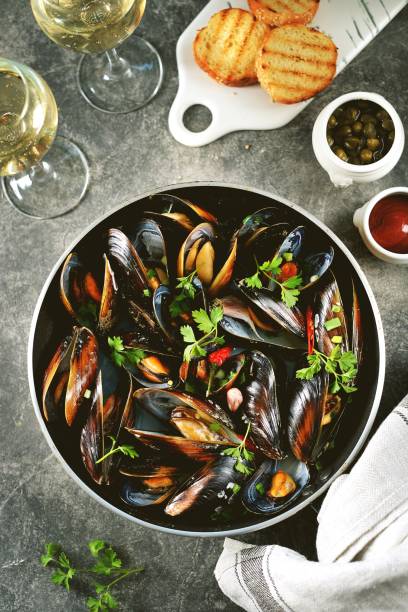 Fresh wild mussels in shells with green onions, garlic, parsley, chili pepper, white wine and olive oil. stock photo