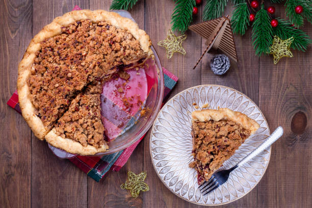 Freshly baked American apple cranberry pie, in baking dish and on plate stock photo