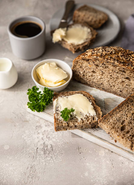 Freshly baked artisan multigrain bread with butter and pate. Breakfast with coffee, sliced bread, butter and liver pate. Light grey background. stock photo
