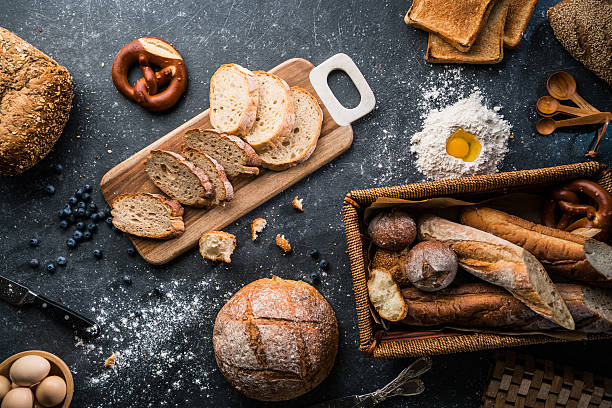 freshly baked bread on wooden table - bakkerij stockfoto's en -beelden