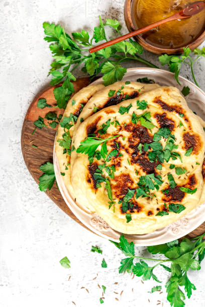 Freshly baked homemade flatbread with oil, spices and parsley. Freshly baked homemade flatbread with oil, spices and parsley. Traditional homemade wheat flour bread on a plate top view. naan bread stock pictures, royalty-free photos & images
