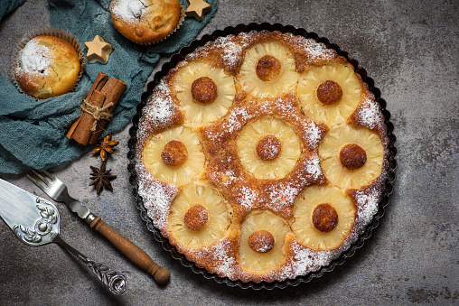 Freshly baked sweet pie with pineapple on a decorative gray-black plant. Stock photo