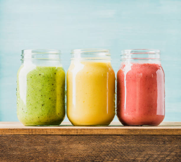 Freshly blended fruit smoothies of various colors and tastes Freshly blended fruit smoothies of various colors and tastes in glass jars. Yellow, red, green. Turquoise blue background orange smoothie stock pictures, royalty-free photos & images