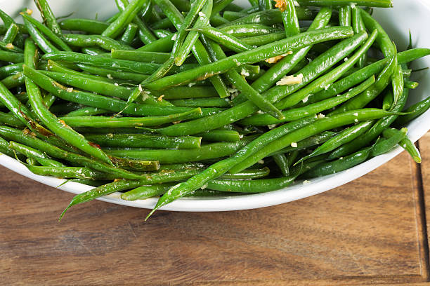 Freshly Cooked Green Beans Horizontal photo of freshly cooked green beans in white bowl on black walnut serving board green bean stock pictures, royalty-free photos & images