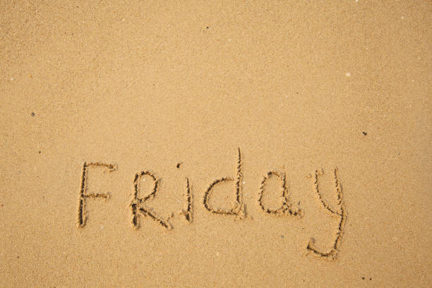 Friday - drawing of days of the week, handwritten on the sea beach sand. stock photo