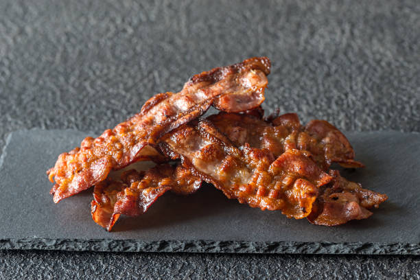 fried bacon strips on the stone dark board - bacon imagens e fotografias de stock