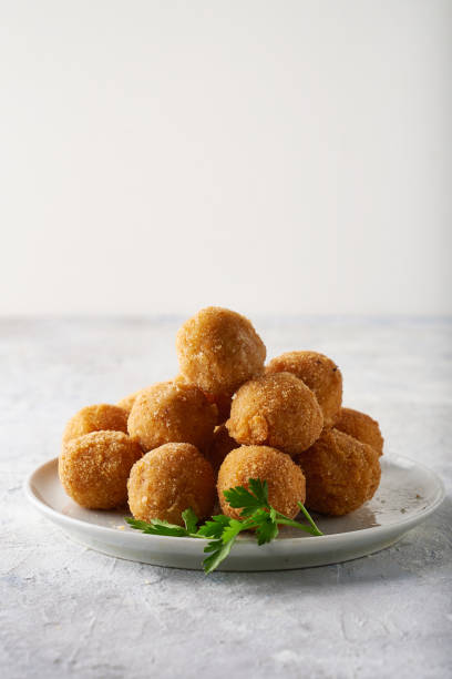 Fried cheese balls, appetizer with herbs and sauces in a plate on a gray table Copyspace stock photo
