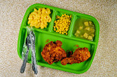 Grade school lunch tray of deep fried chicken legs with macaroni and cheese corn and apple sauce