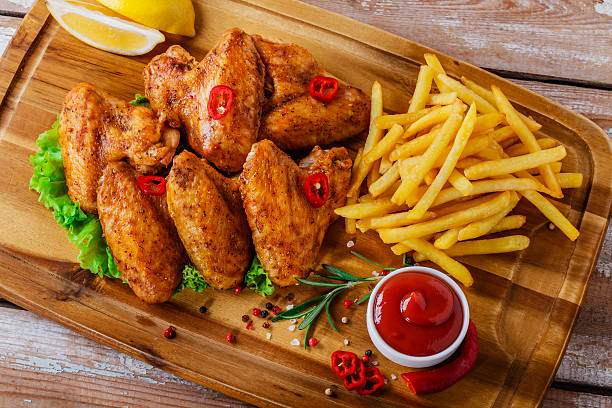 fried chicken wings with red sauce and French fries stock photo