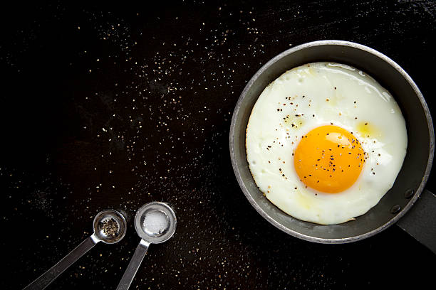 Fried egg "fried egg on skillet, kitchen utensil, salt and pepper." egg yolk photos stock pictures, royalty-free photos & images