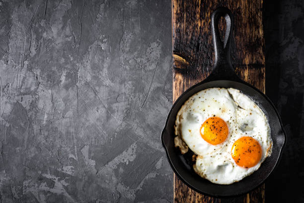 fried eggs in black skillet top view with space for a text stock photo