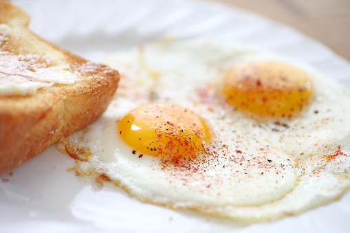two fried eggs sunny side up, sprinkled with smoked paprika and black pepper, toast alongside
