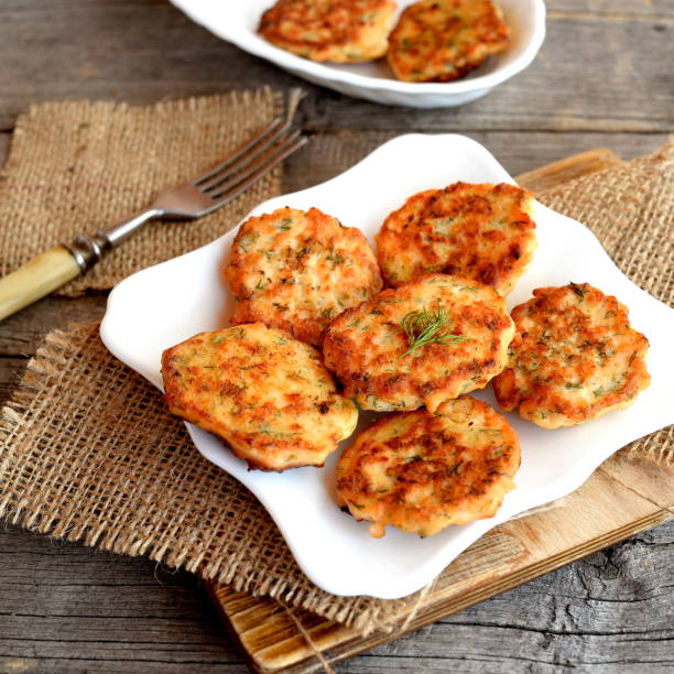 Fried fish cakes on a plate and on an old wooden background. Cutlets cooked from salmon meat. Delicious and nutritious lunch or dinner recipe stock photo
