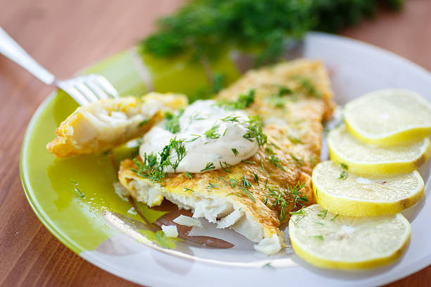 Fried fish with sliced lemons on the side fried fish with sauce and lemon on a plate perch fish stock pictures, royalty-free photos & images