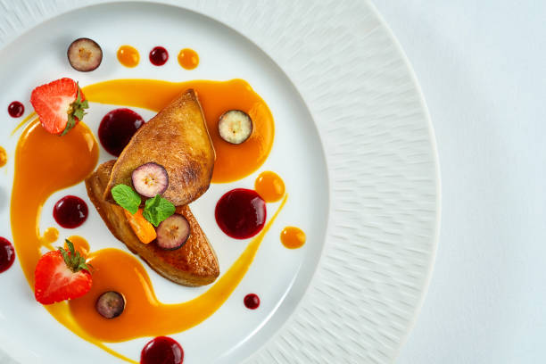 Fried foie gras with berry sauce in a white plate on a white plate stock photo
