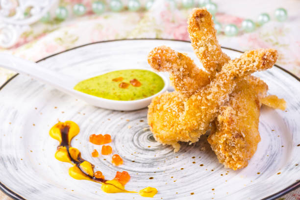 Fried frog legs on plate with lemon sauce food concept stock photo