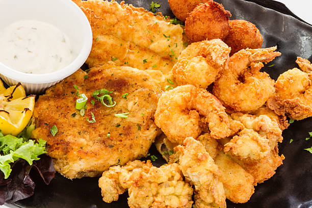 Fried seafood platter. Fried seafood platter with fish, shrimp, oysters, hush puppies, and a crab cake. fried stock pictures, royalty-free photos & images