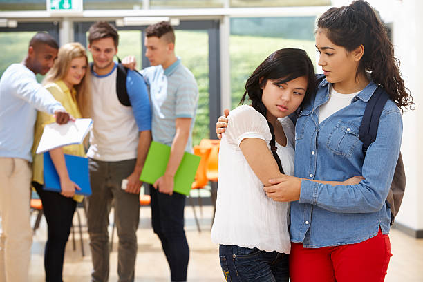 Friend Comforting Victim Of Bullying At School stock photo