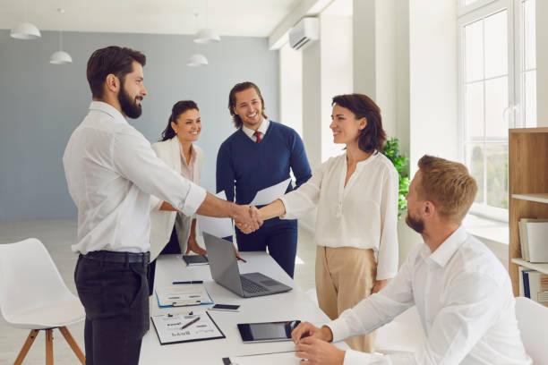 Friendly businesspeople shaking hands confirming a business deal in a negotiation meeting stock photo