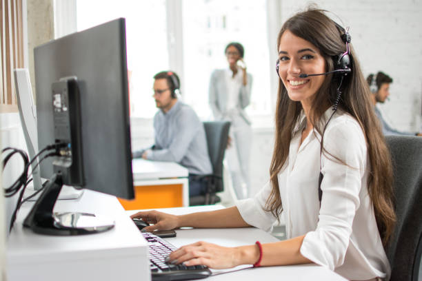 Friendly customer support service operator with headset working in call centre. stock photo