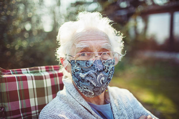 친절한 노인은 바이러스와 박테리아로부터 보호하기 위해 마스크를 착용 - 손수 만든 뉴스 사진 이미지