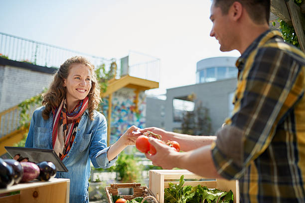 Friendly woman tending an organic vegetable stall at a farmer stock photo