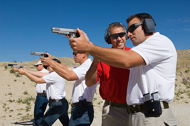 Friends at a firing Range Instructor assisting men aiming hand guns at firing range weapon stock pictures, royalty-free photos & images