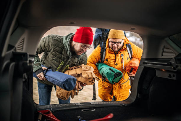 freunde im lager nehmen ausrüstung aus dem kofferraum des autos - auto packen für den urlaub winter stock-fotos und bilder