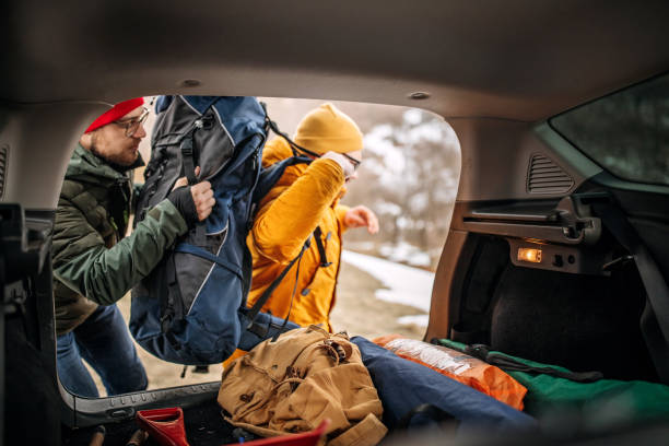 freunde im lager nehmen ausrüstung aus dem kofferraum des autos - auto packen für den urlaub winter stock-fotos und bilder