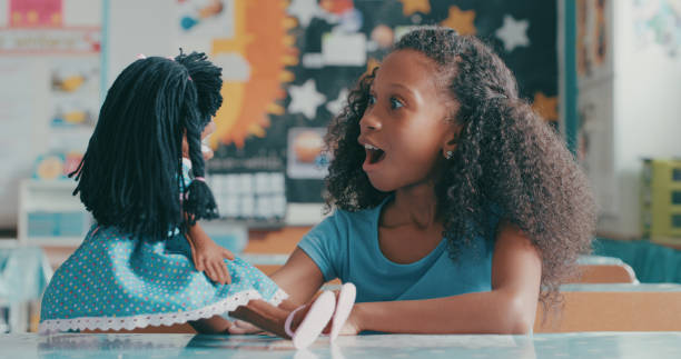 Friends come in all different shapes and sizes Shot of a young girl playing with a doll in a classroom at school doll stock pictures, royalty-free photos & images