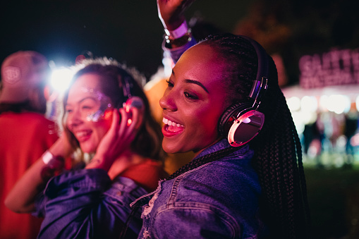 Young women are having fun and dancing in a silent disco at a music festival.
