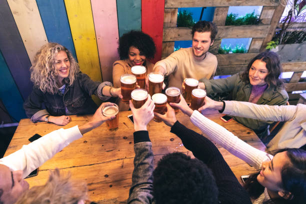 Friends drinking and toasting beer at pub stock photo
