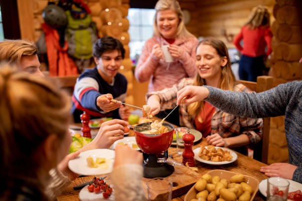 Friends Eating Fondue at Dinner A group of friends eat fondue together at dinner whilst on a skiing holiday. french food photos stock pictures, royalty-free photos & images