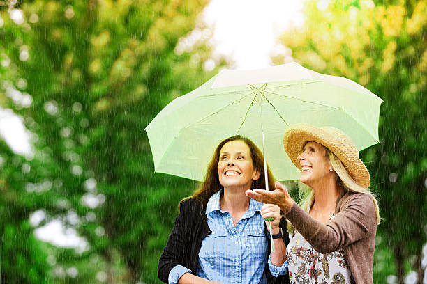 friends in rain - rain woman sun stockfoto's en -beelden
