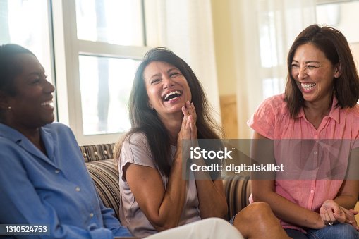 istock Friends laughing and talking sitting at home on the sofa 1310524753