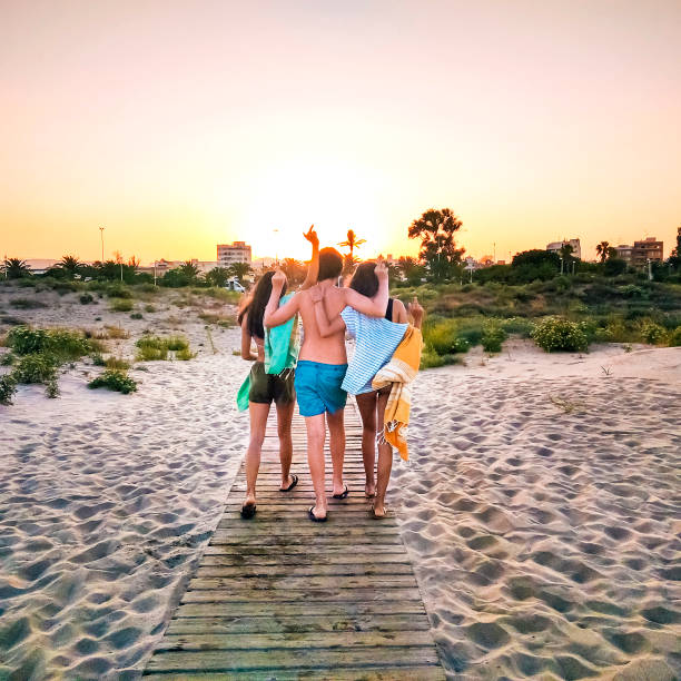 Friends leaving the beach at sunset stock photo