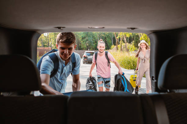 friends load car trunk with baggage stock photo