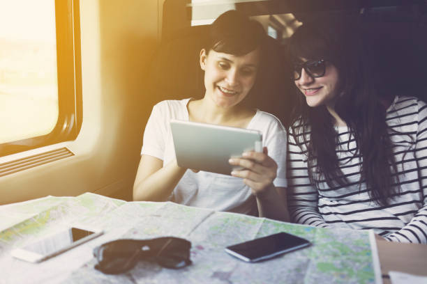 amis regardant tablet pc, voyageant dans un train - smartphone car photos et images de collection