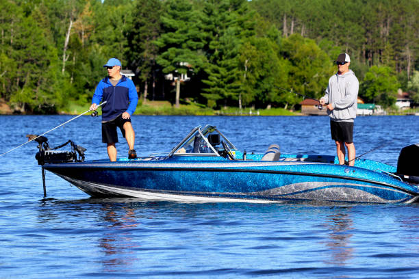 Friends out fishing 2 Two middle aged adult male friends enjoy a day out on the water fishing.  They are fishing a freshwater lake in the Western Great Lakes region of the United States. freshwater fishing stock pictures, royalty-free photos & images