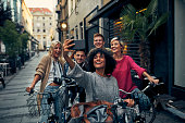 Friends Riding Bicycles In A City. Cycling in pedestrian zone and making selfie.