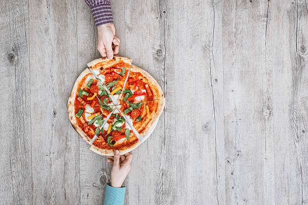 amigos partilhar uma pizza - pizza table imagens e fotografias de stock
