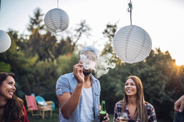 Friends smoking and drinking at a party Young and mixed ethnicity group having fun together, having a party and a gathering, celebrating a birthday. marijuana joint stock pictures, royalty-free photos & images