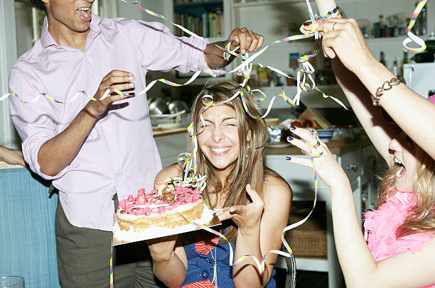 Friends throwing streamers over woman holding cake  20 29 years photos stock pictures, royalty-free photos & images