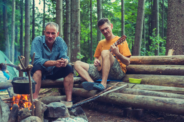 Friends, travelers sit next to a campfire stock photo