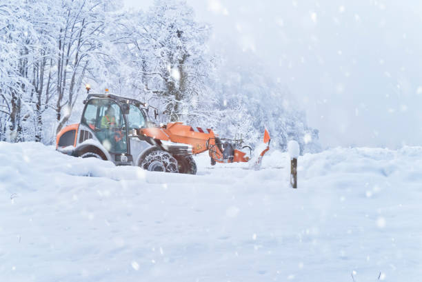 Front loader removes tons of snow from a country road  in heavy snowfall stock photo