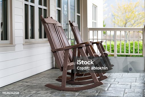 istock Front porch of house with brown rocking chairs and nobody in traditional american house 1153524258