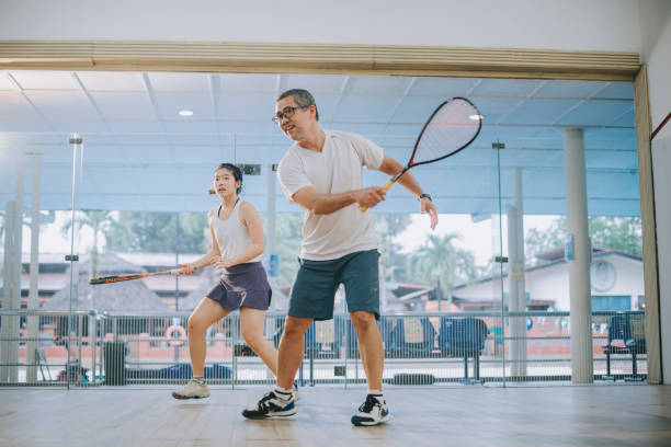 front view Asian squash coach father guiding teaching his daughter squash sport practicing together in squash court Asian squash coach father guiding teaching his daughter squash sport practicing together in squash court do sports stock pictures, royalty-free photos & images