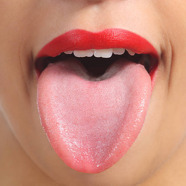 Front view of a woman tongue Close up of a front view of a woman tongue and red painted lips healthy tongue picture stock pictures, royalty-free photos & images