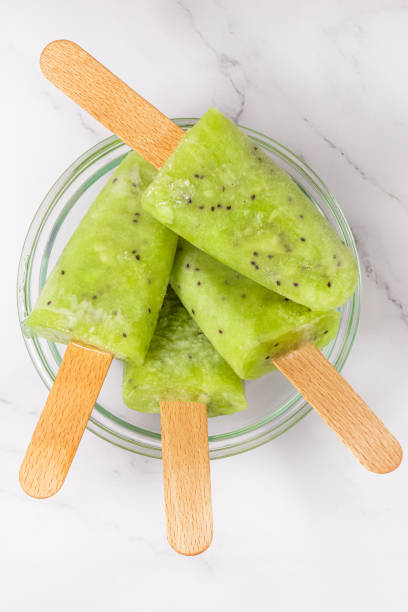 Frozen fruit kiwi juice in a bowl. refreshing Popsicle on a stick. Top view, copy space stock photo